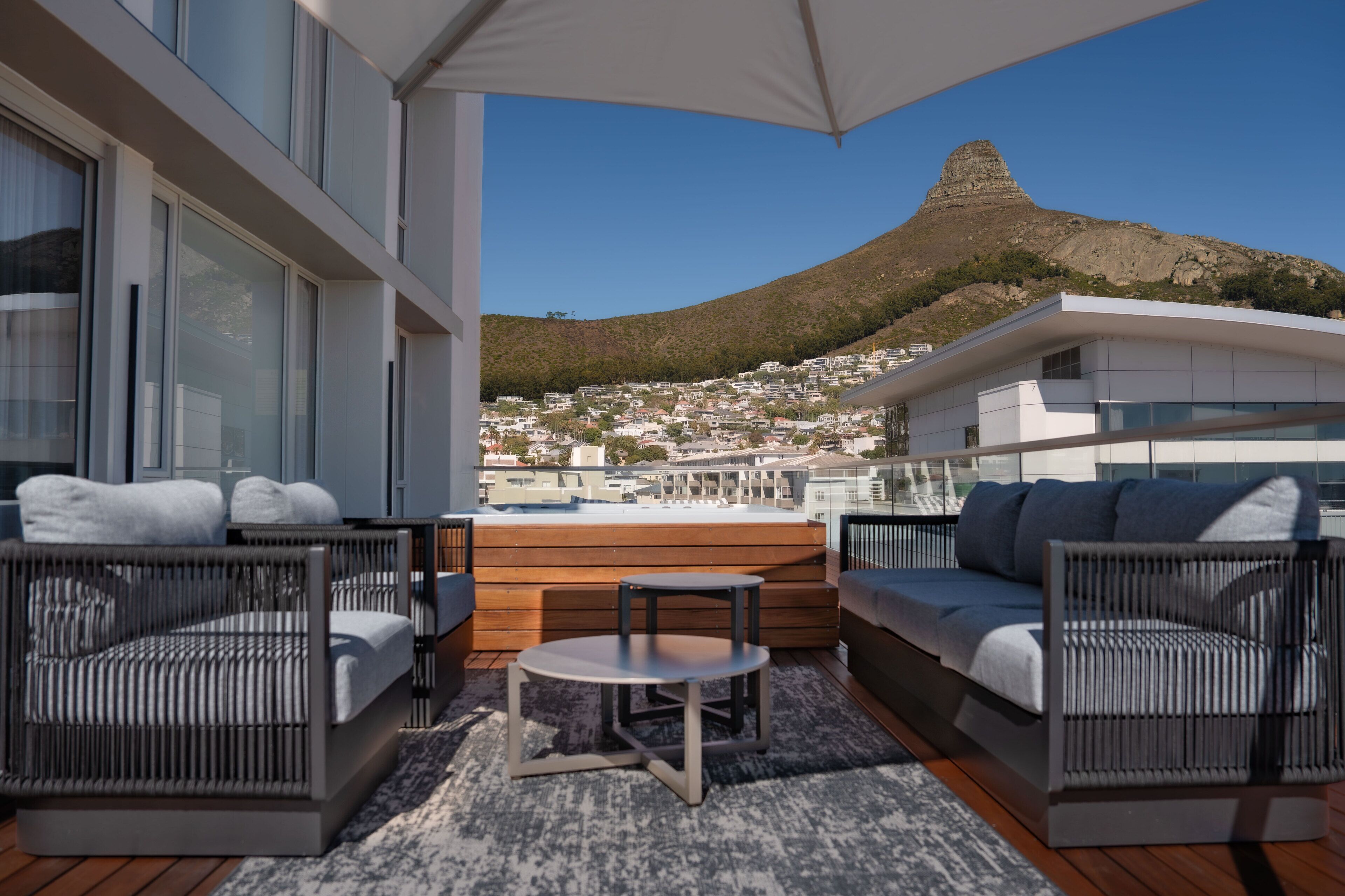 Ein moderner Balkon mit Korbmöbeln, einem kleinen Tisch und Blick auf Berg und Stadt.