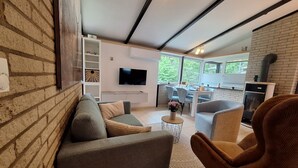 A modern living room with a sofa, armchairs, a TV, and a fireplace.