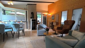 A modern living room with a fireplace, a dining area, and a large window.