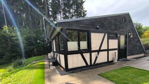 A modern house with a sloped roof, large windows, and a patio area with outdoor furniture.