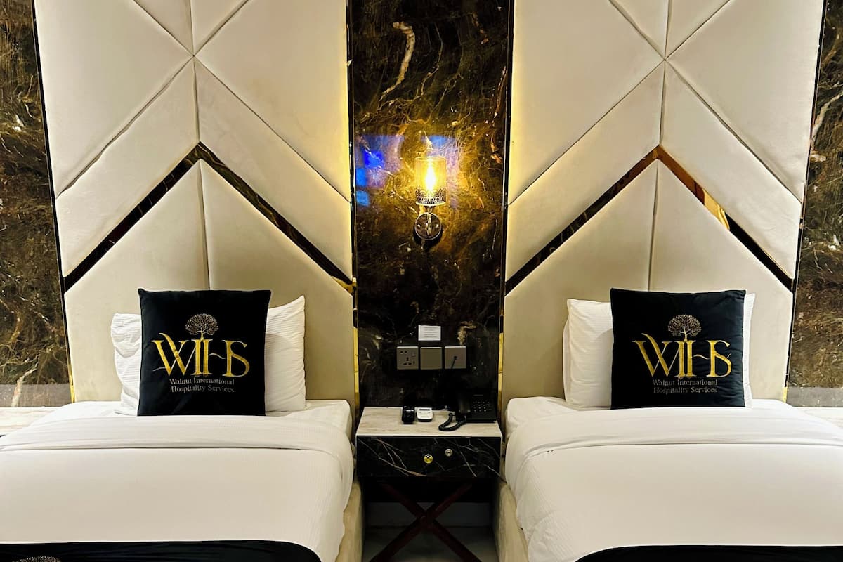 A hotel room with two beds, a central wall mirror, and a marble floor.