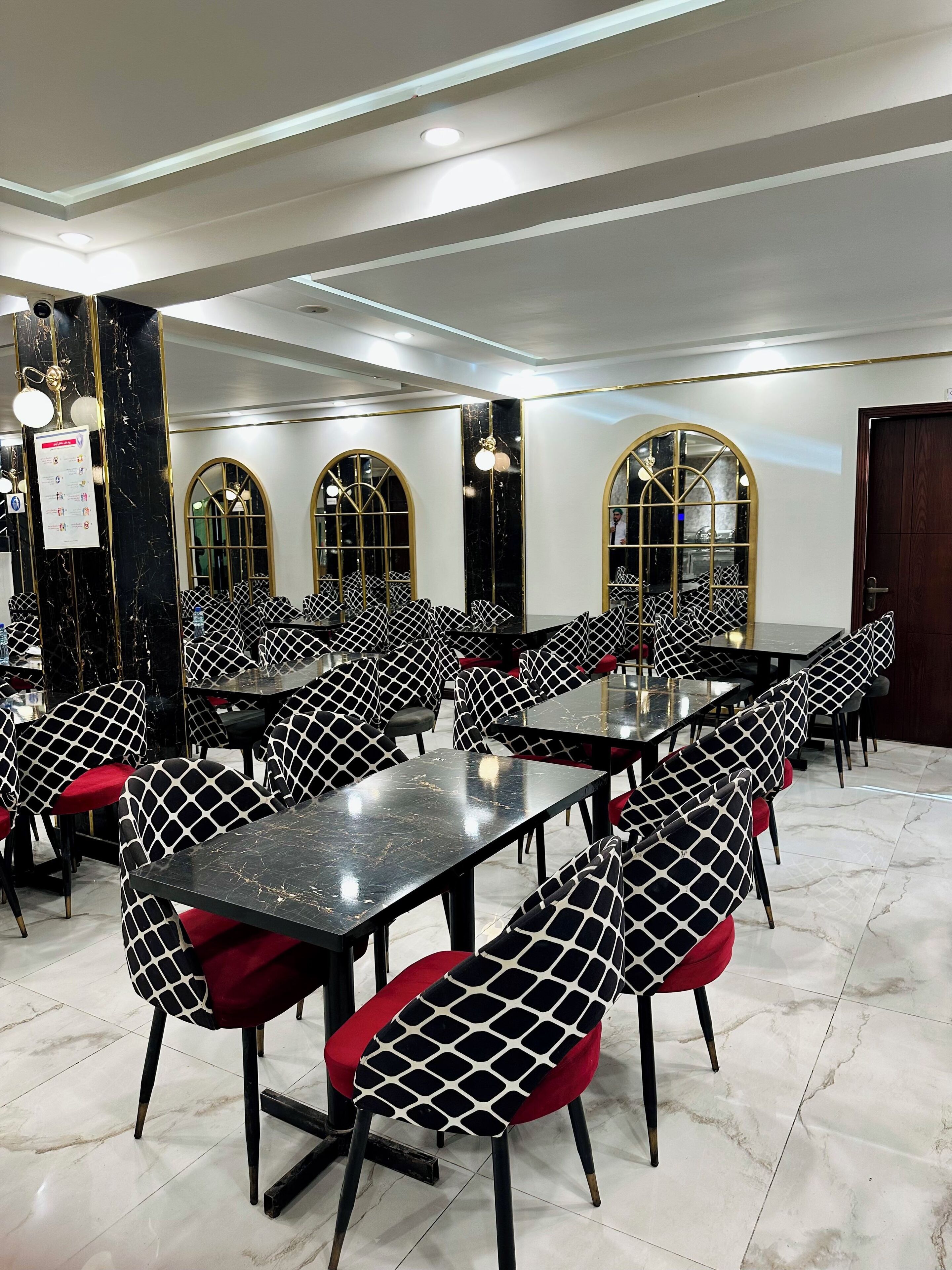 Un espace repas comprenant plusieurs tables et chaises, doté d’un sol en marbre et d’un design de plafond moderne.