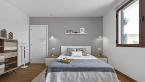 A modern bedroom with a bed, bedside tables, a wardrobe, and a window.