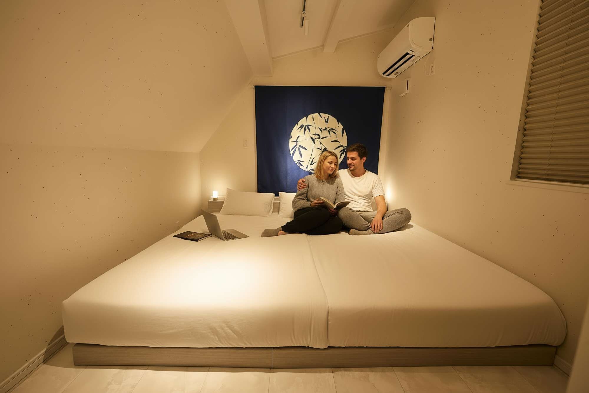 Une chambre avec un lit, un climatiseur fixé au mur et un grand tableau abstrait.