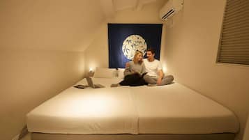 Ein Zimmer mit einem Bett, einer Wand-Klimaanlage und einem großen abstrakten Gemälde.
