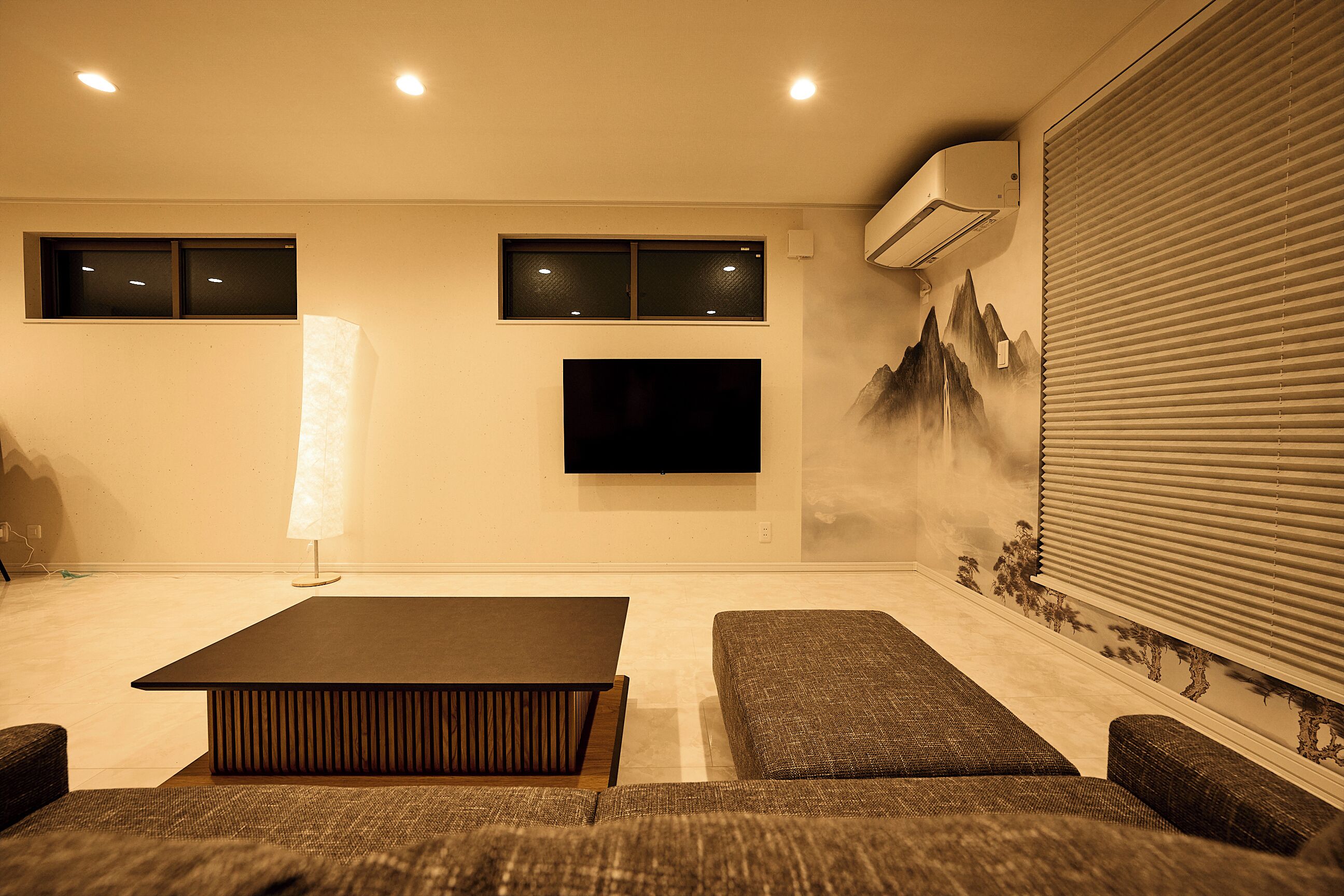 A modern living room with a flat-screen TV, a coffee table, and a sofa.