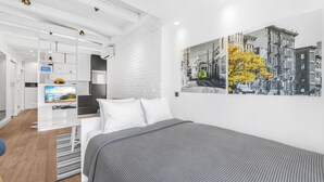 Ein modernes Hotelzimmer mit einem Bett, einem Fernseher, einer weißen Ziegelwand und einem Stadtbild.