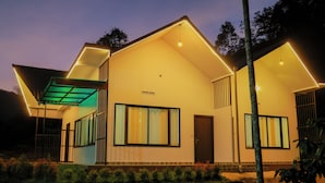 A modern house with large windows and a flat roof, surrounded by a garden. - Prakrithi Luxe Retreat (Vythiri)