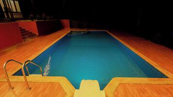 A swimming pool with a wooden deck and metal handrails.