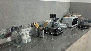 Una cocina con encimera de granito, microondas y diversos utensilios y electrodomésticos.