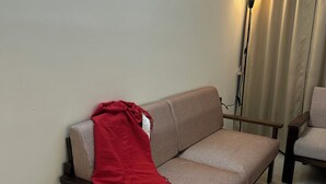 Una sala de estar con un sofá, una manta roja y tres elementos decorativos colgados en la pared.