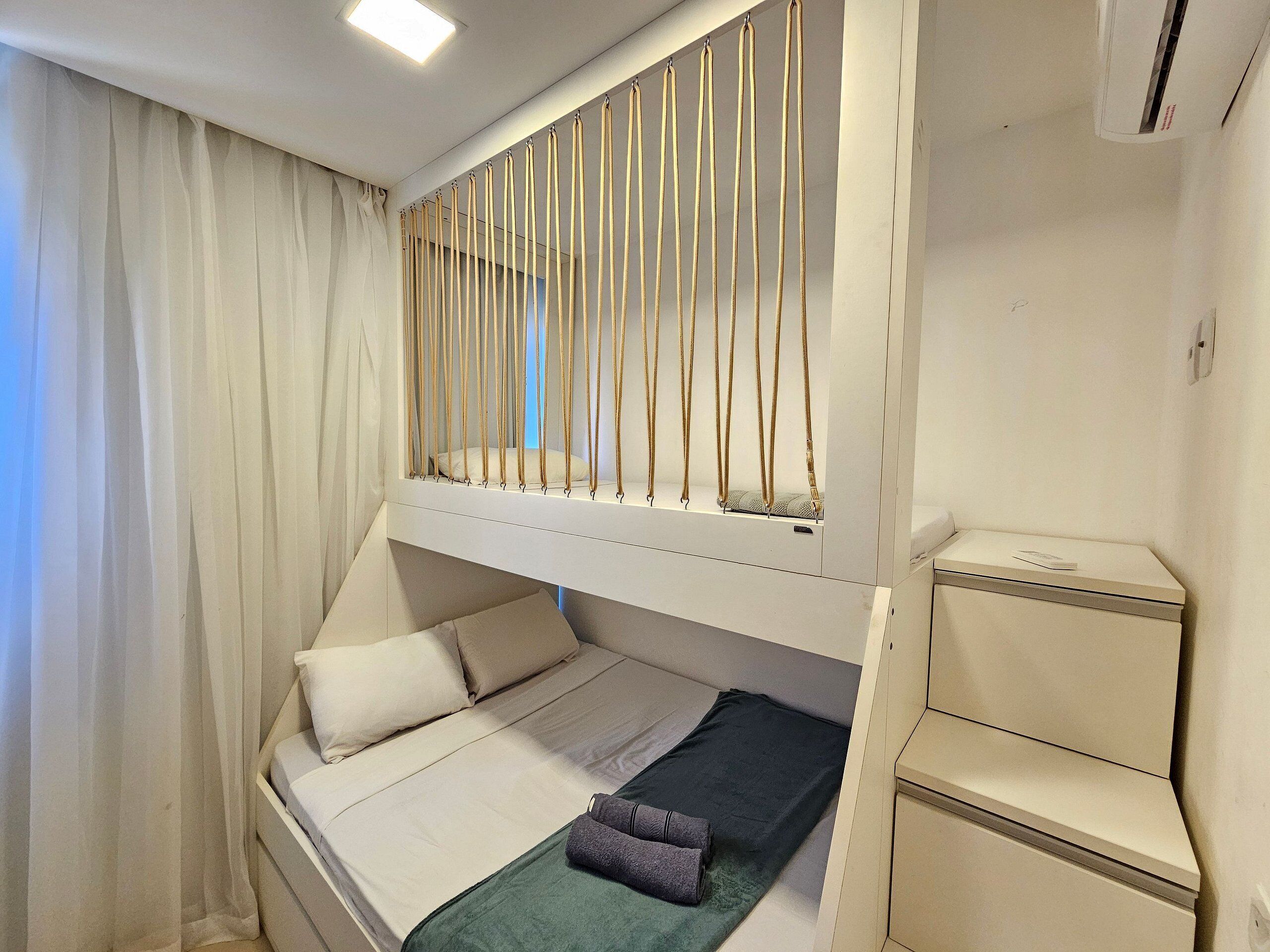 A bunk bed with a pull-up ladder, a bedside table, and a small cabinet.