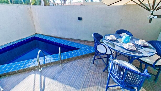 A rooftop pool area with a blue-tiled pool, a round table with chairs, and an umbrella. - Cupe Summer - Porto de Galinhas (Ipojuca)