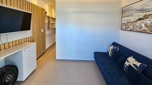 A modern living room with a flat-screen TV, a sofa, and a painting of a beach scene. - Cupe Summer - Porto de Galinhas (Ipojuca)