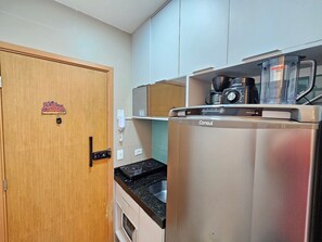 Une cuisine compacte équipée d’un réfrigérateur, d’une cuisinière et d’une machine à café.