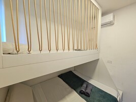 Una cama litera con una cadena dorada colgando, una toalla pequeña y un tapete verde.