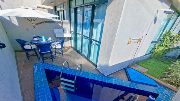 A swimming pool with a diving board, a sunbed, and a table with chairs. - Cupe Summer - Porto de Galinhas (Ipojuca)