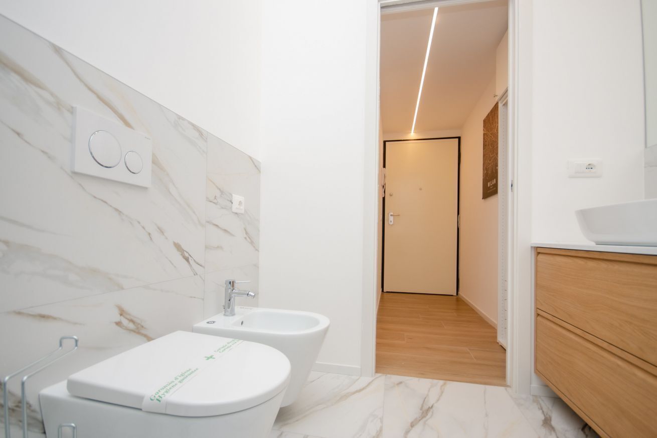 Une salle de bain moderne équipée de toilettes, d’un bidet et d’un meuble-lavabo avec un évier.
