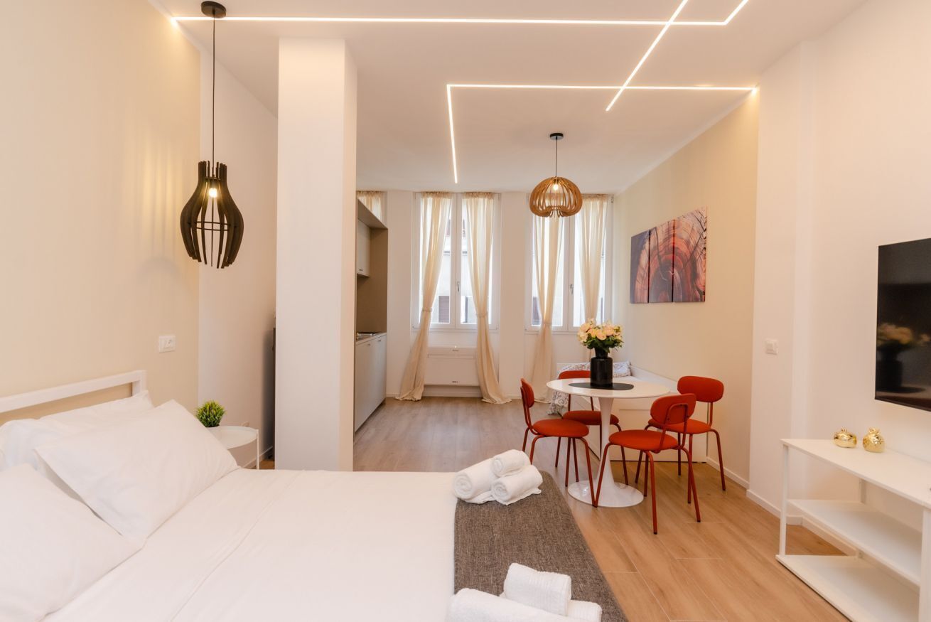 Une chambre d’hôtel moderne équipée d’un lit, d’un bureau avec des chaises, d’un coin repas et d’une télévision.