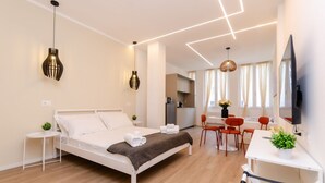 Ein modernes Hotelzimmer mit Bett, Nachttischen, Schreibtisch und Fernseher.