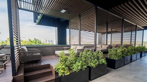 Une terrasse sur le toit avec un revêtement de sol en bois, des jardinières intégrées agrémentées de plantes et des sièges d’extérieur.