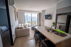 A modern kitchen with a large window, a dining area, and a living space.