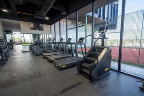 Une salle de sport équipée de tapis de course, de vélos d’appartement et d’appareils de musculation.
