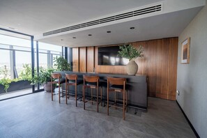 A modern kitchen with a bar area, large windows, and potted plants.