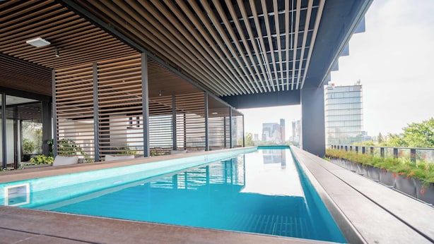 A modern indoor swimming pool with a wooden deck and a city view. - City-view stay near Punto Sao Paulo (Guadalajara)
