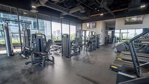 A modern gym with various exercise machines, treadmills, and a large window offering a city view. - City-view stay near Punto Sao Paulo (Guadalajara)