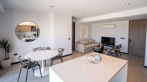 A modern living room with a round dining table, a sofa, a TV, and a large mirror. - City-view stay near Punto Sao Paulo (Guadalajara)