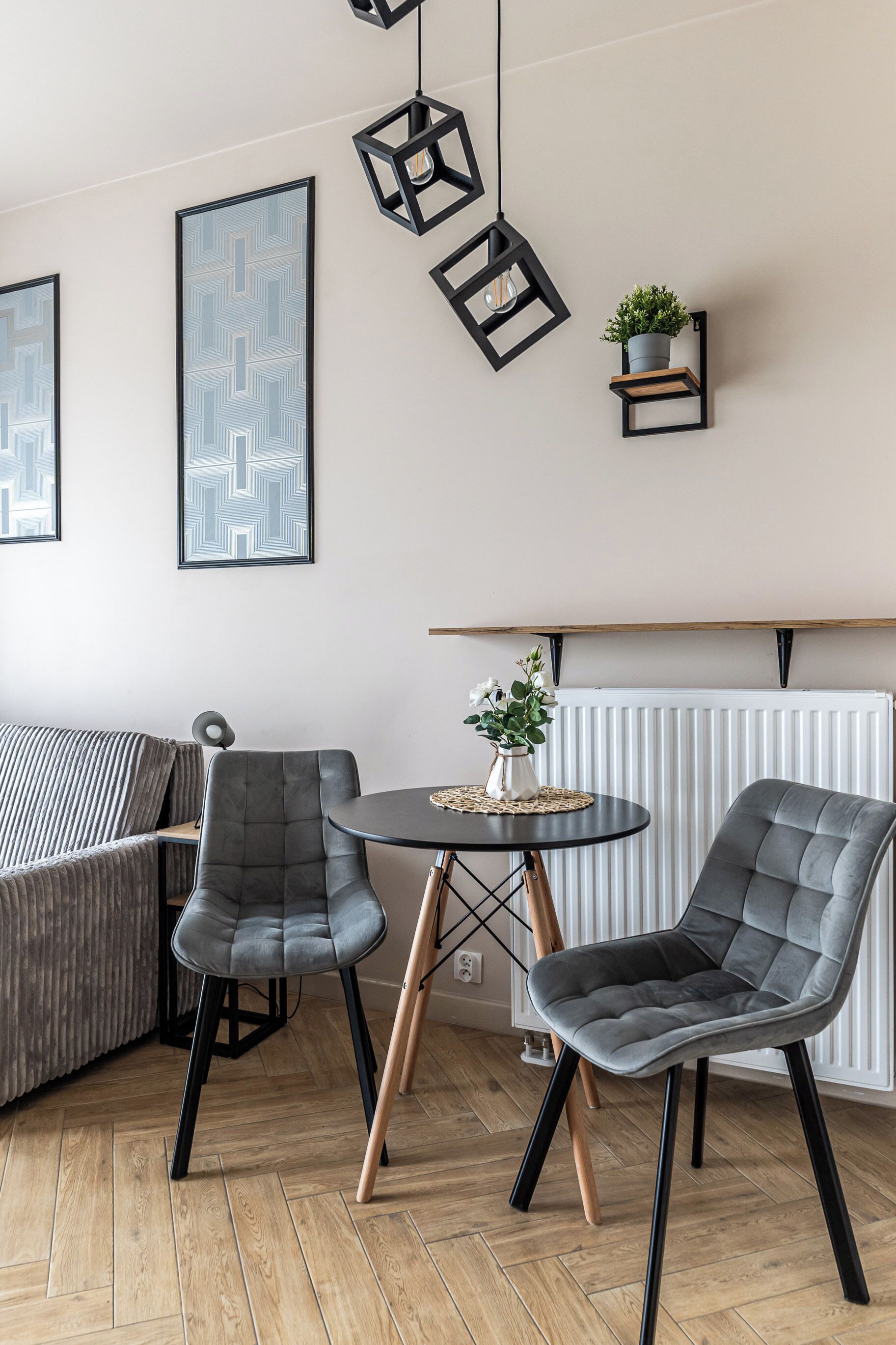 A modern room with a sofa, two chairs, a small table, and a potted plant on a shelf.