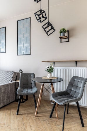 Une pièce moderne comprenant un canapé, deux fauteuils, une petite table et une plante en pot posée sur une étagère.
