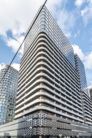A high-rise building with a distinctive wavy facade and multiple balconies. - RentPlanet - Studio Zabrska (Katowice)