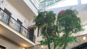 Un atrium à plusieurs niveaux, doté d’un jardin central, de murs en pierre et d’un balcon orné de balustrades en fer forgé.