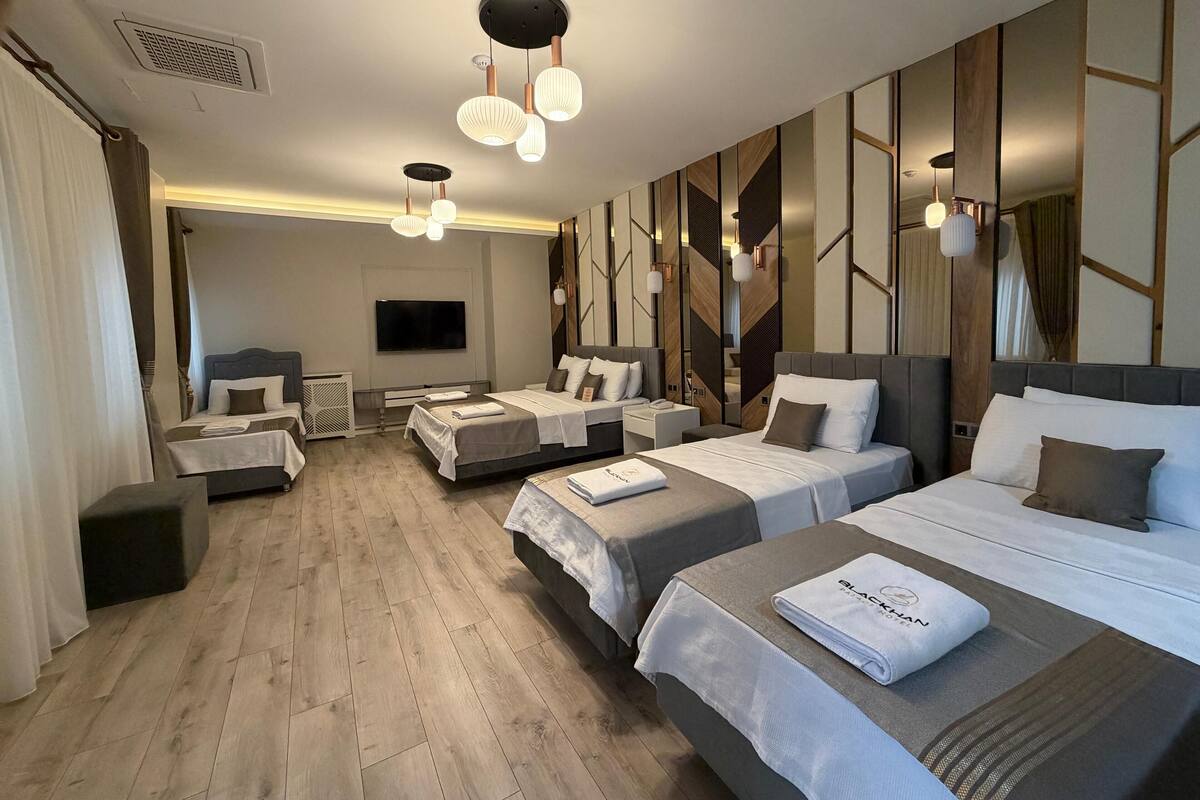 Ein modernes Hotelzimmer mit zwei Betten, einem Flachbildfernseher und einer Sitzecke.