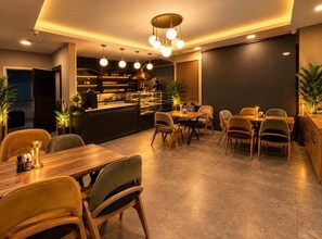 A modern dining area with a bar, multiple seating arrangements, and ambient lighting.