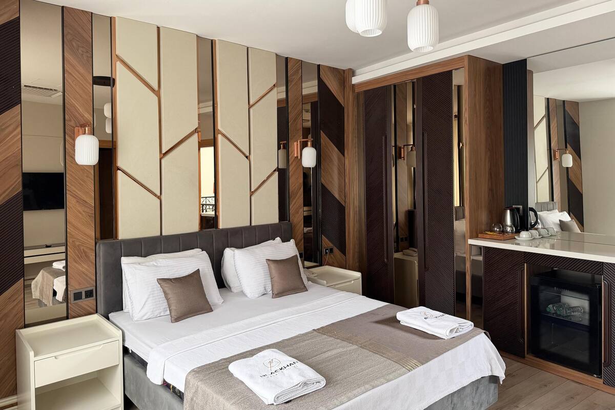 Ein modernes Hotelzimmer mit einem großen Bett, Nachttischen, einem Schreibtisch und einer Minibar.