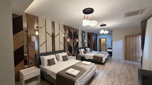 Une chambre d’hôtel moderne, dotée d’un grand lit, de tables de chevet, d’un miroir et d’une salle de bain visible à travers une porte ouverte.