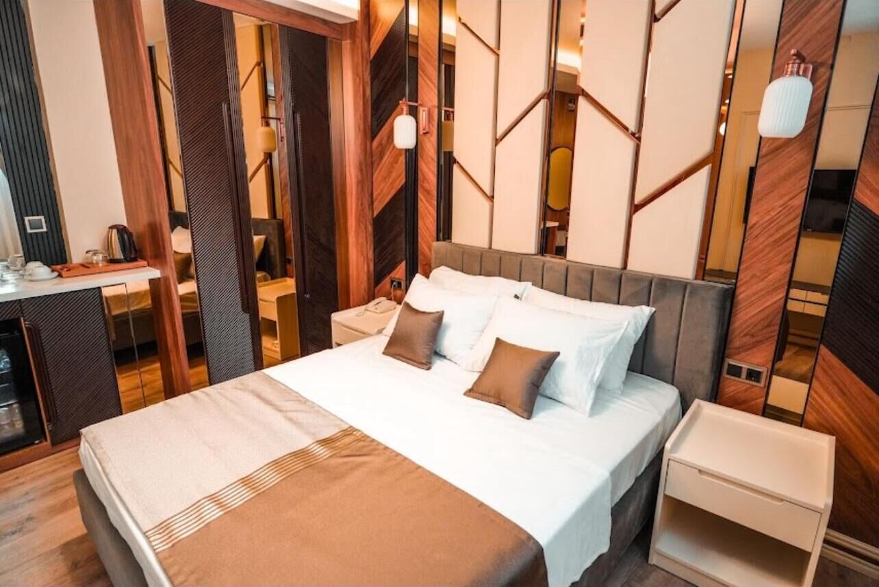 Una habitación de hotel moderna con una cama grande, mesitas de noche y un espejo.