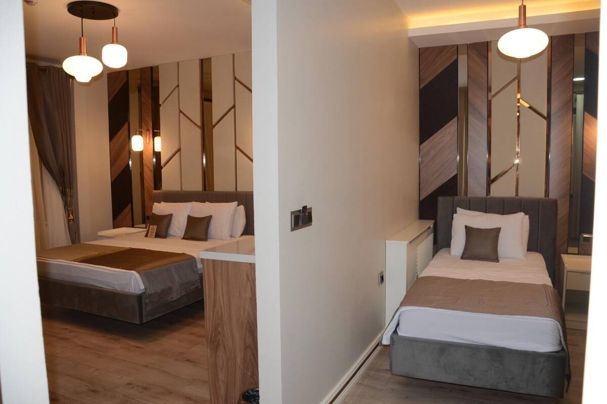 Ein modernes Hotelzimmer mit zwei Betten, Holzvertäfelung und Pendelleuchten.