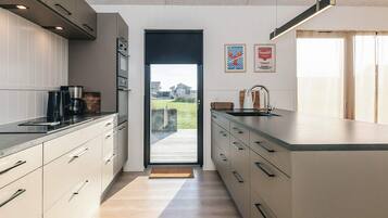 A modern kitchen with a large island, stainless steel appliances, and a view of the outdoors.