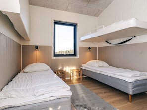 A room with two bunk beds, a window, and a small table.