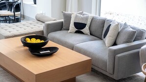 A modern living room with a grey sofa, a wooden coffee table, and a bowl of lemons. - Arabian Ranches Villa Sleeps 9 Near Golf Courses (Dubai)