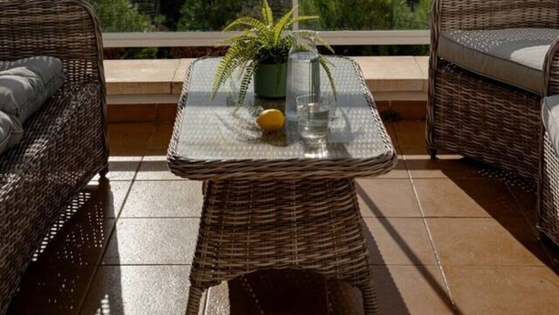 A balcony with wicker furniture, a glass table, and a view of the sea. - Stylish 2BR Apt | Balcony & Sea Views (Benalmádena)