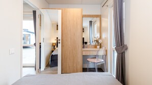 A bedroom with a bed, a desk, a chair, and a window with curtains. - Tiny Home 'Laura' with Mountain Views, Wi-Fi, and Air Conditioning (Untergriesbach)