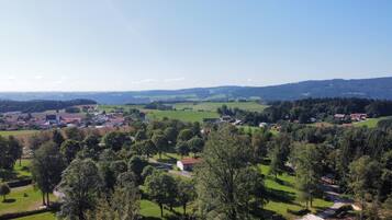 A rural landscape with a church, houses, and rolling hills.