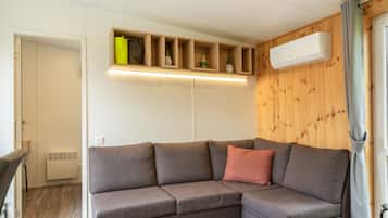 Ein modernes Wohnzimmer mit einer Eckcouch, eingebauten Regalen und einer Klimaanlage.