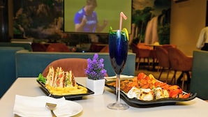 A dining table with a meal, a drink, and a small plant. - V Hotel TSSG (New Delhi)