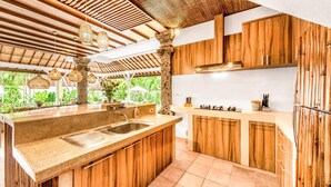 Una cocina con armarios de madera, encimera de granito, un lavamanos y una estufa.
